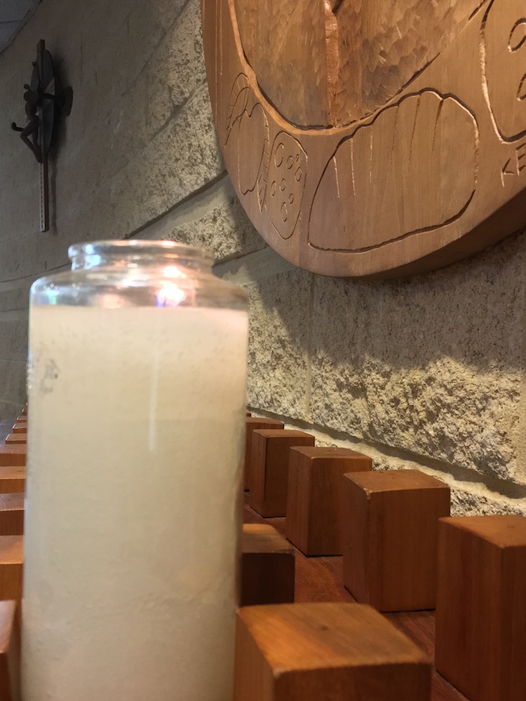 Lighted candle with cruxific of Jesus Christ and bread in background