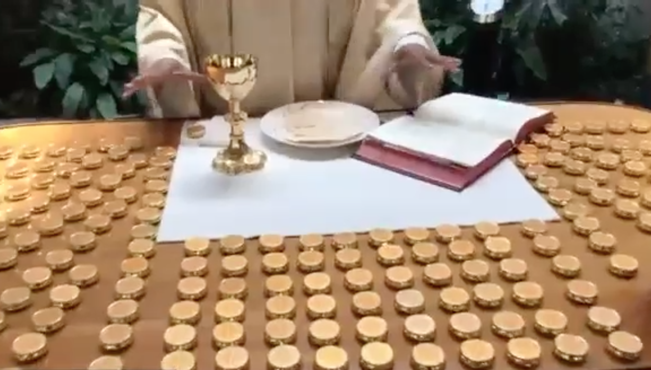 Priest hands over altar with bread, wine, and many Eucharist pyx